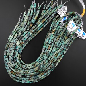 May include: A strand of turquoise beads, each bead is a rectangular shape with a mottled green and brown pattern. The beads are strung on a clear thread and are ready to be used for jewellery making.