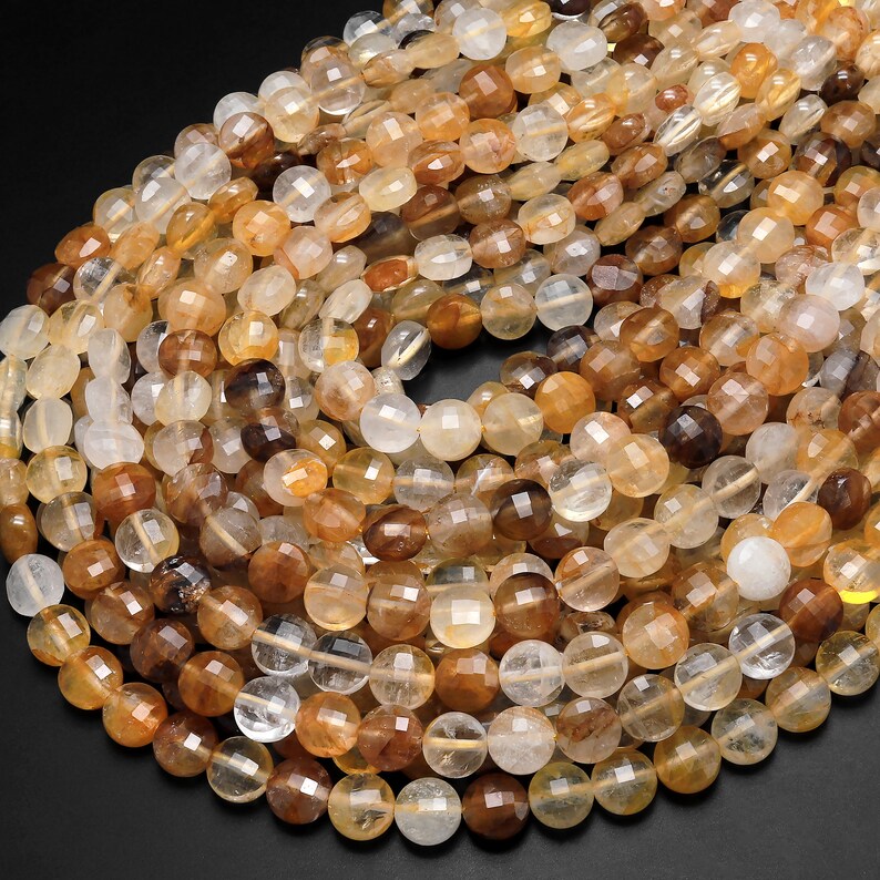 May include: A strand of faceted, round, translucent beads in shades of light brown, yellow, and clear. The beads are made of natural quartz crystal.