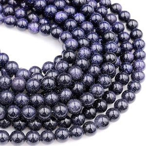 Op de afbeelding: Een streng donkerblauwe edelsteen kralen. De kralen zijn rond en hebben een gevlekte, glinsterende textuur.