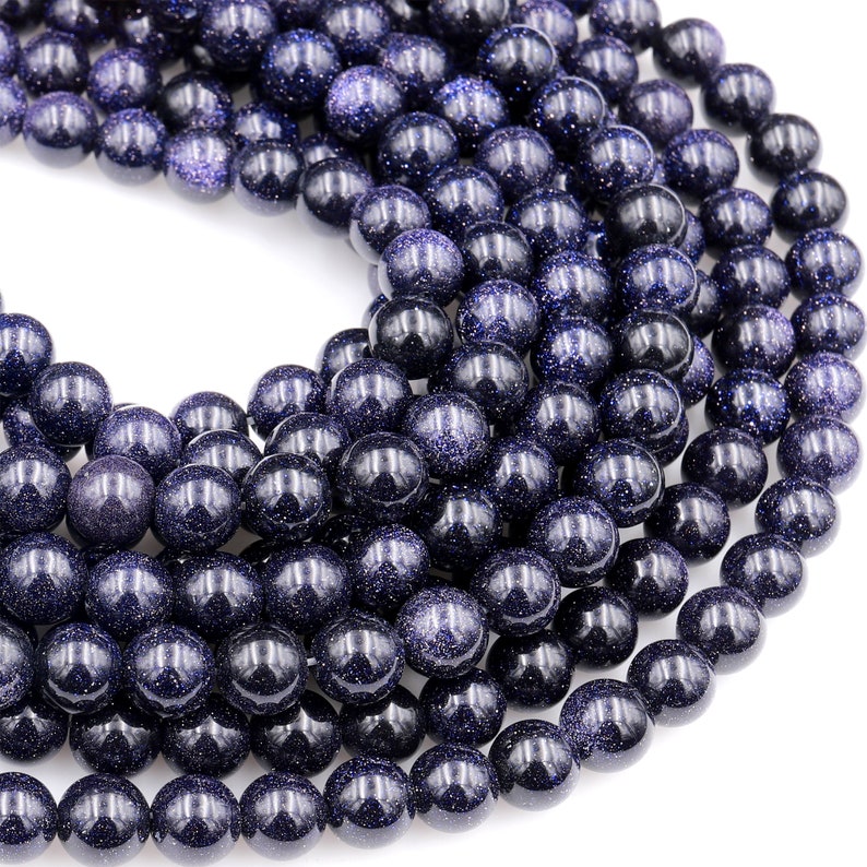 Op de afbeelding: Een streng donkerblauwe edelsteen kralen. De kralen zijn rond en hebben een gevlekte, glinsterende textuur.