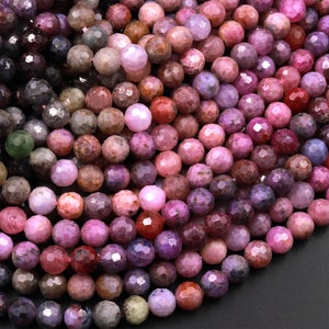 Può includere: Una collana di perline di pietre preziose sfaccettate in tonalità rosa, viola e grigio. Le perline sono rotonde e hanno una forma leggermente irregolare.