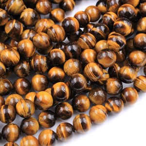 May include: A strand of round, golden brown tiger's eye beads. The beads have a smooth, polished finish and a subtle shimmer.