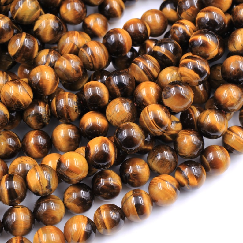 May include: A strand of round, golden brown tiger's eye beads. The beads have a smooth, polished finish and a subtle shimmer.