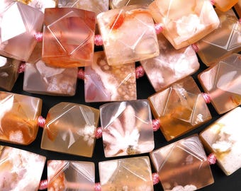 Pode incluir: Close-up de um colar com contas de ágata translúcidas de corte quadrado em tons de laranja, pêssego e branco. As contas são enfiadas com um cordão rosa, criando um padrão geométrico. As contas de ágata têm padrões internos únicos.
