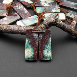 May include: Two rectangular pieces of green, white, and brown agate with a brown string tied through holes at the top.