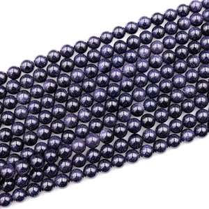 Op de afbeelding: Een streng donkerblauwe ronde edelsteen kralen. De kralen hebben een gevlekte, glinsterende textuur.