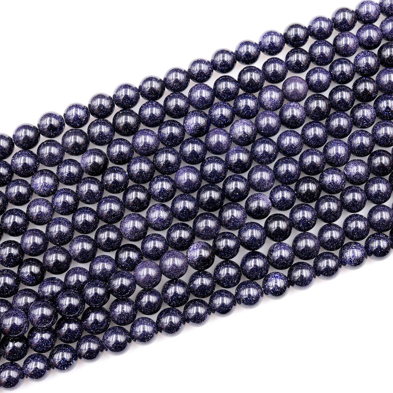 Op de afbeelding: Een streng donkerblauwe ronde edelsteen kralen. De kralen hebben een gevlekte, glinsterende textuur.