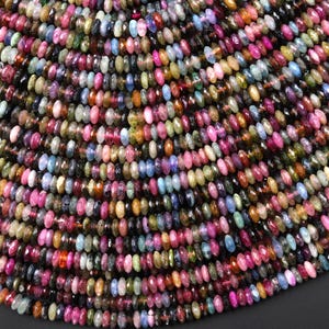 May include: Close-up of a collection of multi-coloured gemstone beads. The oval-shaped, faceted beads display pink, green, blue, and yellow hues. The beads are strung together, creating a textured surface. Ideal for jewellery making.