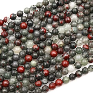 May include: A strand of round, green, red, and white gemstone beads. The beads are approximately 8mm in diameter and have a speckled, cloudy appearance.