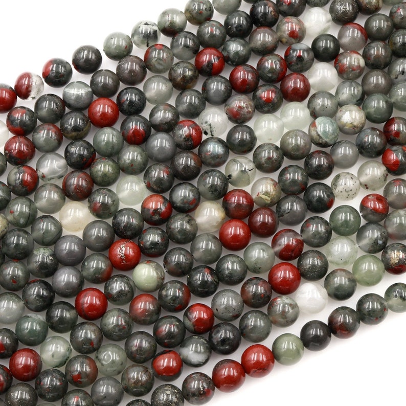 May include: A strand of round, green, red, and white gemstone beads. The beads are approximately 8mm in diameter and have a speckled, cloudy appearance.