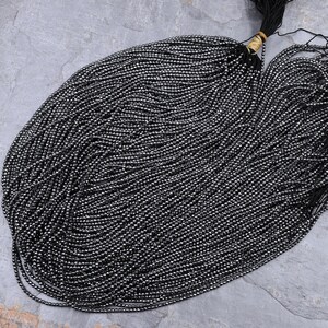May include: A strand of black hematite beads, approximately 2mm in diameter, with a shiny, metallic finish. The beads are strung on a thin thread and are ready for jewelry making.