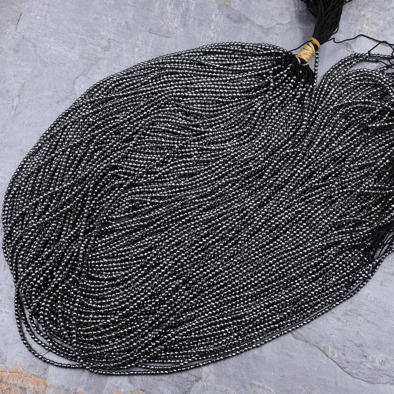 May include: A strand of black hematite beads, approximately 2mm in diameter, with a shiny, metallic finish. The beads are strung on a thin thread and are ready for jewelry making.