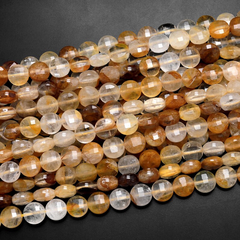 May include: A strand of round, faceted, translucent beads in shades of light brown, yellow, and clear. The beads are made of natural quartz crystal.