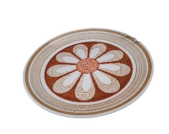 May include: A white ceramic plate with a brown and white daisy design. The daisy has a brown center and white petals with brown lines.
