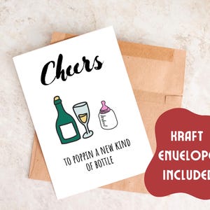 Pode incluir: Um cart&atilde;o branco com o texto "Cheers to poppin' a new kind of bottle" e ilustra&ccedil;&otilde;es de uma garrafa de champanhe, uma ta&ccedil;a de champanhe e uma mamadeira. O cart&atilde;o est&aacute; sobre um envelope marrom com o texto "Kraft Envelopes Included" em vermelho.