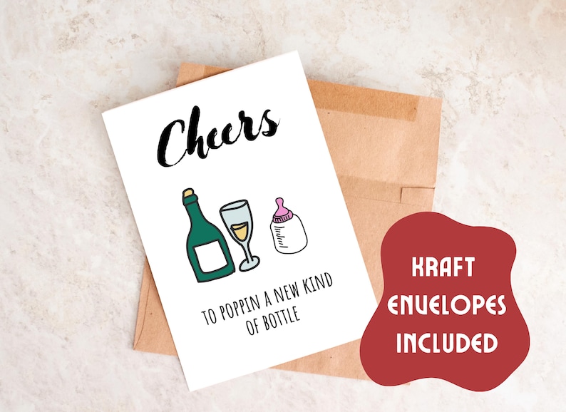 Pode incluir: Um cart&atilde;o branco com o texto "Cheers to poppin' a new kind of bottle" e ilustra&ccedil;&otilde;es de uma garrafa de champanhe, uma ta&ccedil;a de champanhe e uma mamadeira. O cart&atilde;o est&aacute; sobre um envelope marrom com o texto "Kraft Envelopes Included" em vermelho.