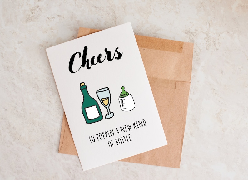 Pode incluir: Um cart&atilde;o branco com texto preto que diz "Cheers to poppin' a new kind of bottle". O cart&atilde;o tem um desenho de uma garrafa de vinho, um copo de vinho e uma mamadeira.