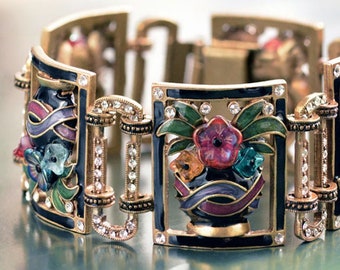 May include: A gold-tone bracelet with a black enamel base and colorful enamel flowers in a vase design. The bracelet is adorned with clear rhinestones.