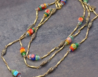 May include: A multi-strand necklace with gold chain links and colorful glass beads. The beads are round and have a variety of floral patterns.