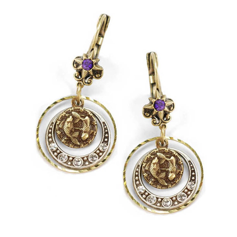 May include: Gold tone dangle earrings with a purple gemstone and a circular charm featuring two fish. The charm is surrounded by a double circle design with clear rhinestones.