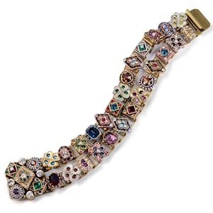 May include: A multi-colored bracelet with a gold-tone finish. The bracelet is made up of small, intricately designed links, each featuring a different colored gemstone. The bracelet has a clasp closure.