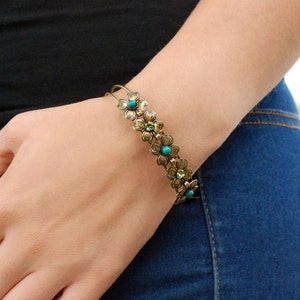 May include: A gold-toned bracelet with a floral design featuring turquoise and green gemstones.
