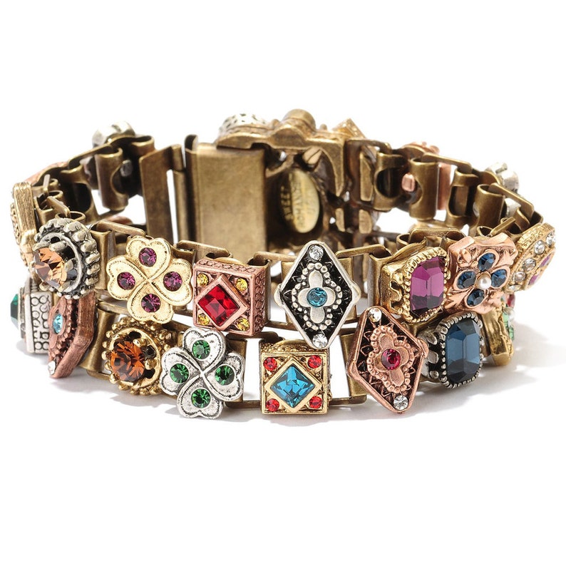 May include: A gold-tone bracelet with a chain link design and multiple colorful, jeweled charms. The charms include squares, diamonds, and four-leaf clovers.