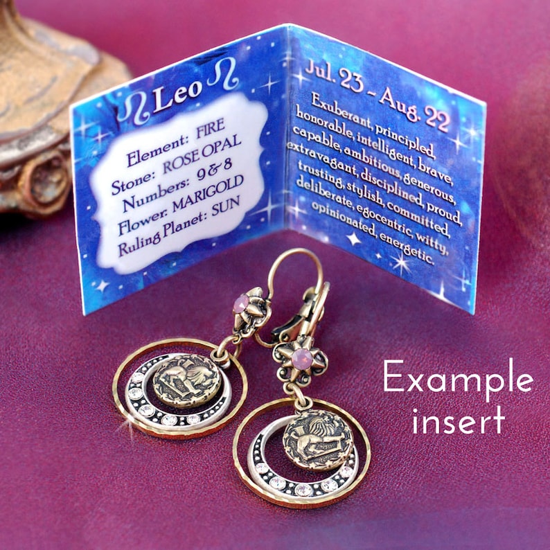May include: Gold tone earrings with a pink stone and a circular design featuring the astrological symbol for Leo. The earrings are accompanied by a card with the text "Leo" and information about the astrological sign, including its element, stone, numbers, flower, and ruling planet. The text on the card reads "Jul. 23 - Aug. 22 Exuberant, principled, honorable, intelligent, brave, capable, ambitious, generous, extravagant, disciplined, proud, trusting, stylish, committed, deliberate, egocentric, witty, opinionated, energetic."