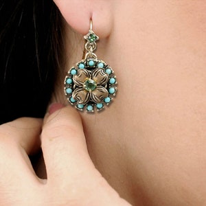 May include: A pair of gold-tone earrings with a turquoise and green gemstone flower design.