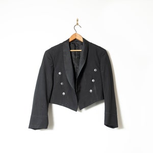 May include: A black short-sleeved jacket with a satin collar and silver buttons.