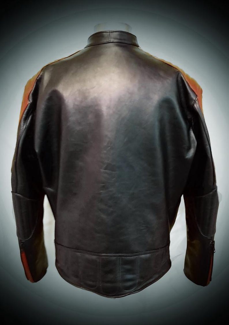 May include: Black leather jacket with orange and red accents on the shoulders and sleeves. The jacket has a classic design with a stand-up collar and a fitted silhouette. The back view shows the jacket's details, including the stitching and panels.