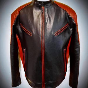 May include: Black and red leather jacket with a stand-up collar and a front zipper. The jacket features red accents on the shoulders, pockets, and zipper trim. A stylish, modern design.