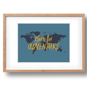 May include: Framed print with a dark blue world map silhouette on a teal background. The words "Born for ADVENTURE" are written in yellow, in a handwritten style. The frame is made of light-coloured wood.