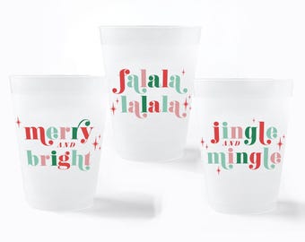 Puede incluir: Tres vasos de plástico esmerilado con texto navideño en rojo y verde. El vaso izquierdo dice merry and bright, el central falala lalala y el derecho jingle and mingle, todos decorados con pequeños gráficos en forma de estrella.