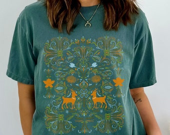 May include: A teal blue t-shirt with a vintage-inspired floral pattern featuring two deer in orange. The pattern is in shades of blue, green, and orange.