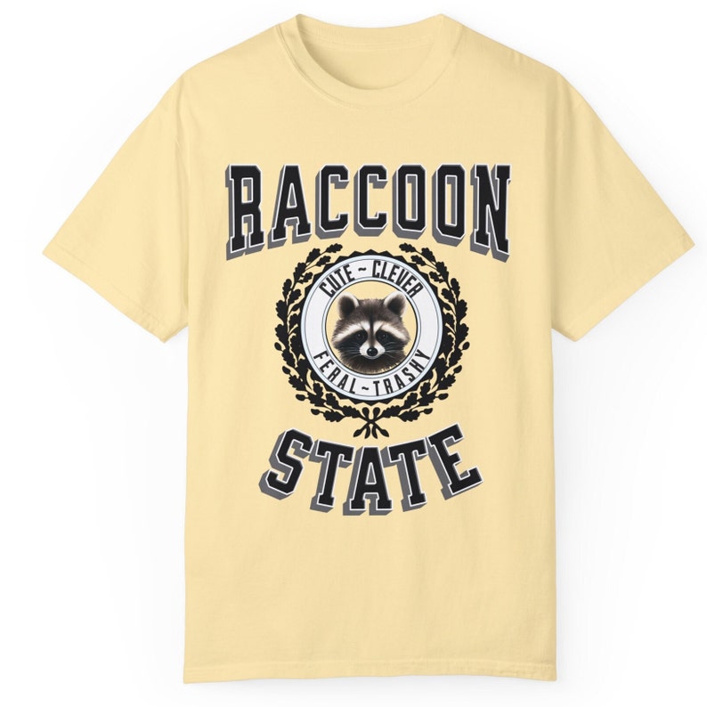 May include: A yellow t-shirt with a black and white graphic of a raccoon in a circle with the words "RACCOON STATE" above and below the circle. The circle also has the words "Cute - Clever" above the raccoon and "Feral - Trashy" below the raccoon.