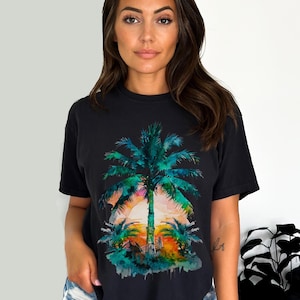 May include: Black t-shirt featuring a watercolor design of a palm tree at sunset. The palm tree is rendered in shades of green and blue, with a vibrant orange and pink sunset in the background. The shirt is a casual, short-sleeved style.