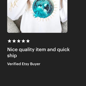 Puede incluir: Sudadera blanca con un gr&aacute;fico dorado de un signo zodiacal de Acuario. El gr&aacute;fico presenta a una mujer con cabello azul y un dise&ntilde;o celestial. Las palabras "Aquarius" est&aacute;n escritas en dorado en la manga.