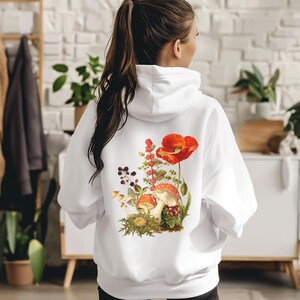 May include: White hoodie with a floral print featuring red poppies, mushrooms, and green leaves.
