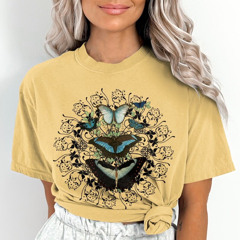 May include: A yellow t-shirt with a graphic of blue butterflies and black floral designs.