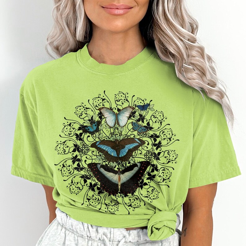 May include: A light green t-shirt with a black and white graphic of butterflies and floral designs.