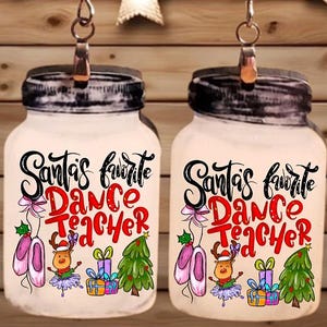 Op de afbeelding: Oorbellen in de vorm van potten met de tekst "Santa's Favorite Dance Teacher". De oorbellen hebben illustraties van balletschoenen, een rendier, cadeaus en een kerstboom. De oorbellen hangen aan zilverkleurige haken.