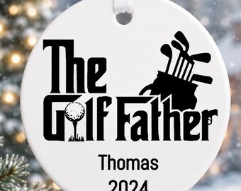 Puede incluir: Adorno navideño redondo blanco con el texto negro "The Golf Father". Presenta una pelota y palos de golf. El adorno incluye el nombre "Thomas" y el año "2024". Una cinta blanca está adjunta para colgarlo.