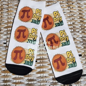 May include: White socks with a black toe and heel, featuring a Pi Day design. The design includes a pie graphic with the pi symbol and the text "Pi Day 3.14". These socks are a fun and festive accessory.