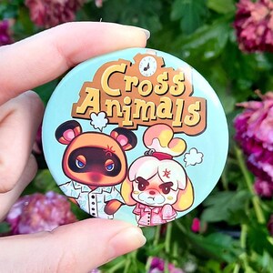 May include: A blue and brown button with the text "Cross Animals" and images of two animal characters from the video game Animal Crossing. The characters are a brown dog with a white shirt and a white dog with a pink shirt.