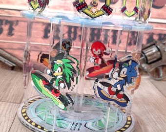 Puede incluir: Un carrusel de acrílico transparente con personajes de Sonic the Hedgehog. El carrusel tiene una base circular y una parte superior transparente con detalles en amarillo y rojo. Personajes: Sonic, Jet y Knuckles.