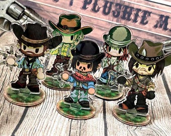 May include: Five acrylic character standees featuring chibi-style figures in western attire, including cowboy hats, bandanas, and holsters. Each figure stands on a circular base with a green grassy print, arranged in a group on a wood-grain surface.