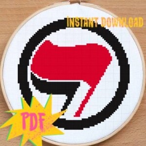 May include: A black and white cross-stitch pattern of the anarchist symbol, a red fist breaking through a circle. The pattern is in a PDF format and is available for instant download.