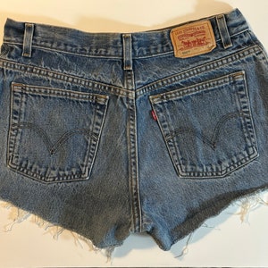 May include: Blue denim shorts with frayed edges and a Levi's brand patch on the back pocket.