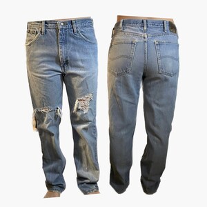 May include: A pair of light blue denim jeans with distressed details. The jeans have a straight leg fit and are ripped at the knees.